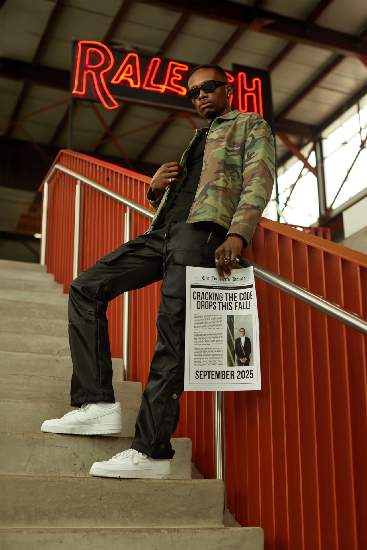 Bobby McNeil Jr. holding a newspaper with 'Cracking the Code Drops This Fall!' headline